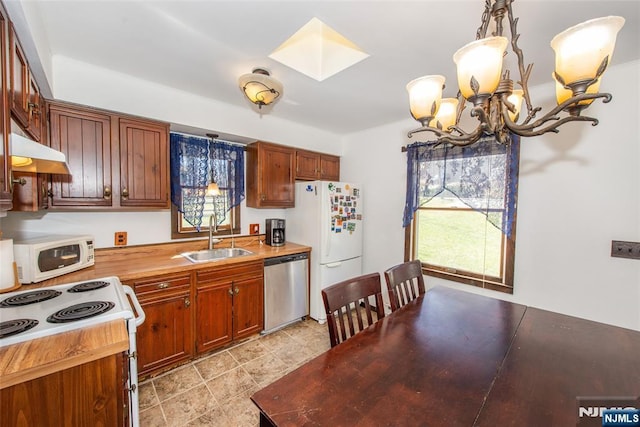 kitchen with a chandelier, white appliances, under cabinet range hood, and a sink