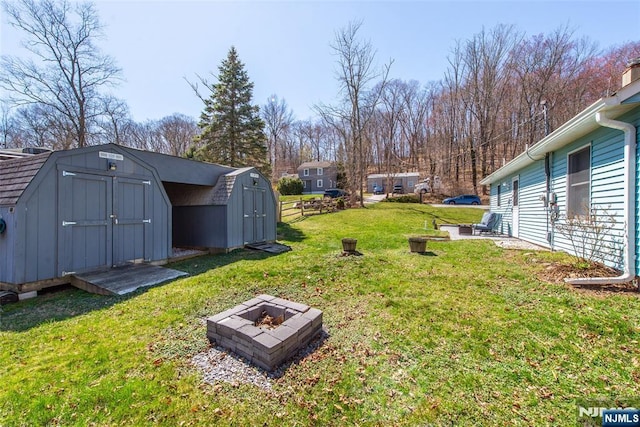 view of yard featuring a fire pit, an outdoor structure, and a storage shed