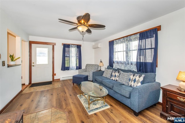 living room with wood finished floors, an AC wall unit, a ceiling fan, baseboards, and baseboard heating