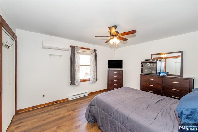 bedroom with a wall mounted air conditioner, a ceiling fan, wood finished floors, a baseboard heating unit, and baseboards