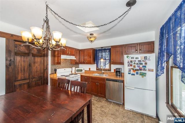 kitchen with under cabinet range hood, light countertops, a sink, white appliances, and a chandelier