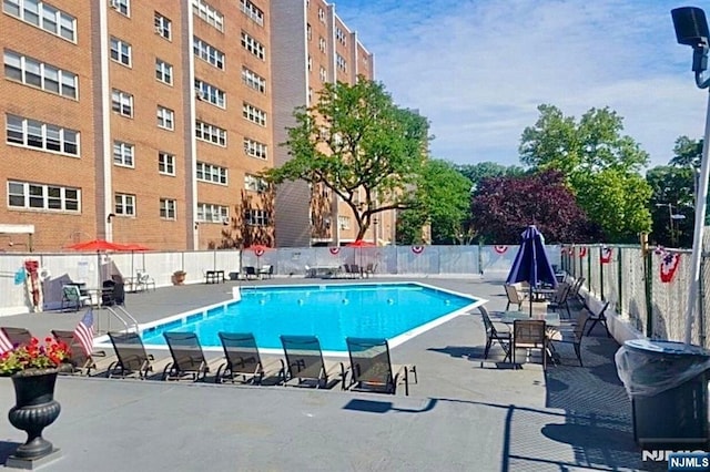 community pool with fence and a patio
