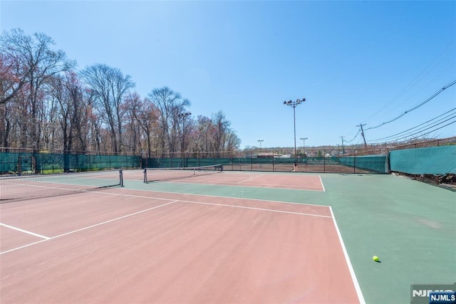view of tennis court featuring community basketball court and fence