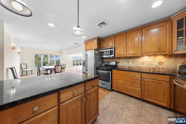 4 Colony Rd, Edgewater, NJ 07020 - kitchen with brown cabinetry, visible vents, an inviting chandelier, backsplash, and appliances with stainless steel finishes