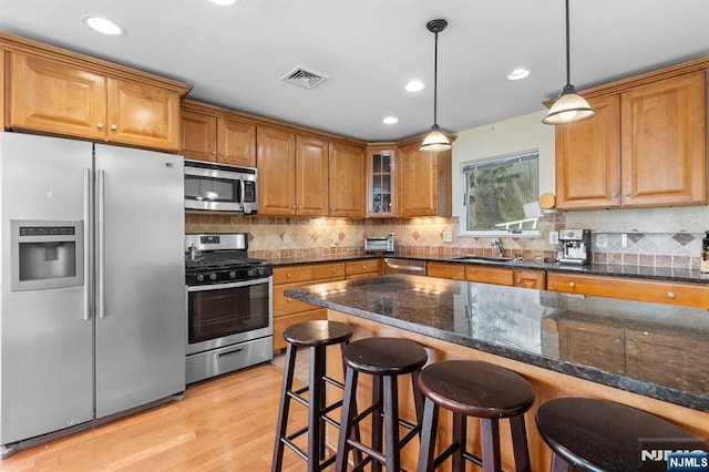 4 Colony Rd, Edgewater, NJ 07020 - kitchen with brown cabinets, appliances with stainless steel finishes, a breakfast bar area, visible vents, and light wood-style floors