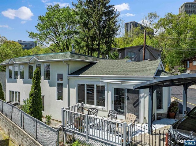 4 Colony Rd, Edgewater, NJ 07020 - back of house with stucco siding, roof with shingles, fence private yard, and a patio