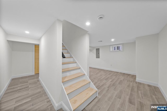 stairway with electric panel, baseboards, wood finished floors, and recessed lighting