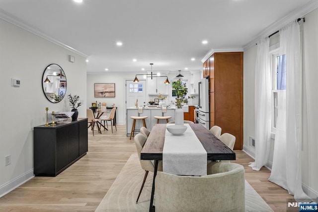 dining room featuring baseboards, recessed lighting, light wood-style floors, and crown molding