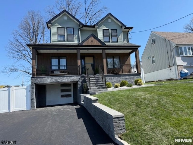 view of front of property featuring a front lawn, driveway, stone siding, an attached garage, and a porch