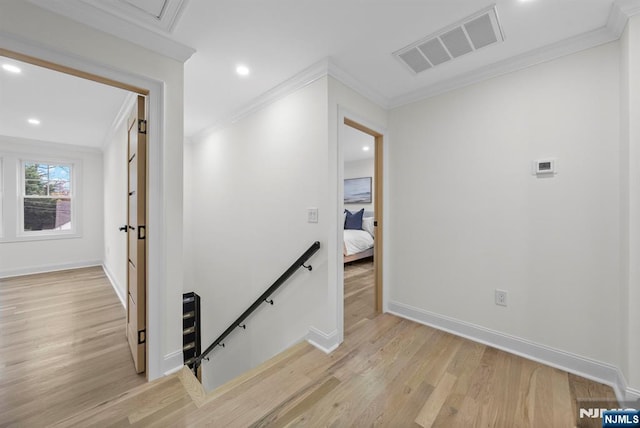 hallway featuring crown molding, an upstairs landing, light wood-style floors, baseboards, and visible vents