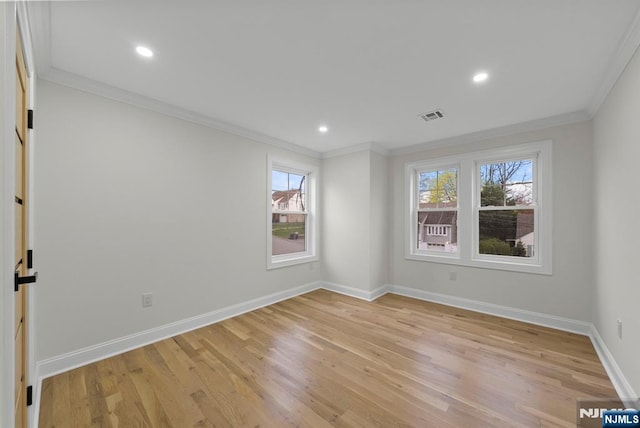 spare room featuring baseboards, ornamental molding, light wood-style floors, and visible vents