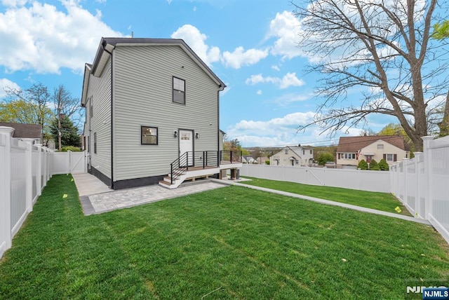 rear view of property featuring a yard, a patio area, and a fenced backyard