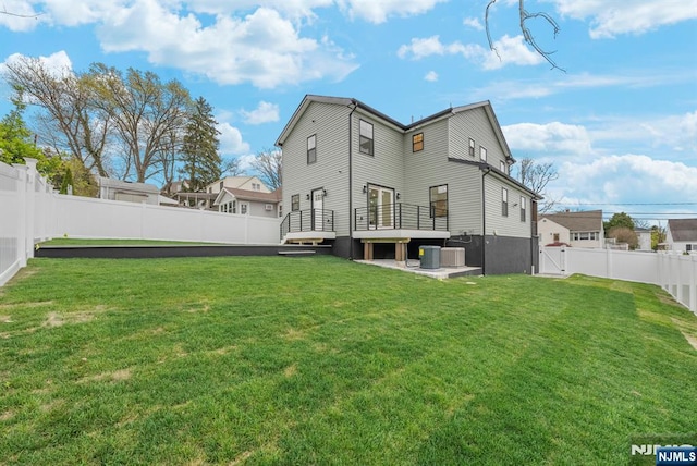 rear view of property with a wooden deck, a yard, cooling unit, and a fenced backyard