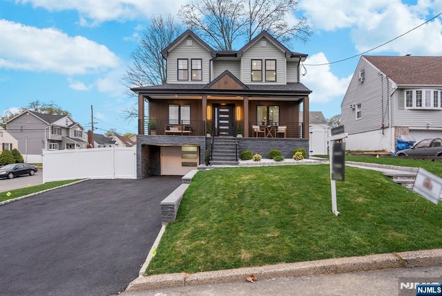 craftsman-style house featuring a front lawn, driveway, a porch, stone siding, and fence