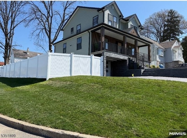 exterior space with stairs, a front yard, and fence