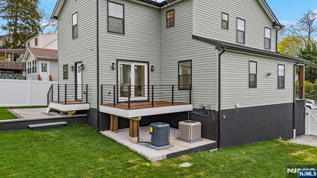 back of property featuring fence, a yard, and central AC unit