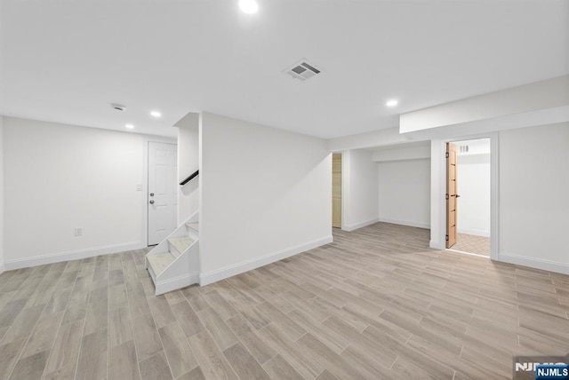 finished basement with light wood-type flooring, baseboards, visible vents, recessed lighting, and stairs