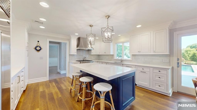 19 Merrill Dr, Mahwah, NJ 07430 - kitchen with wall chimney range hood, white cabinets, a kitchen bar, a kitchen island, and crown molding
