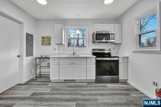 14 Harvey Rd, West Milford, NJ 07421 - kitchen featuring wood finished floors, a sink, stainless steel appliances, light countertops, and white cabinetry