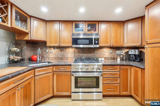 kitchen with a sink, appliances with stainless steel finishes, decorative backsplash, and brown cabinets