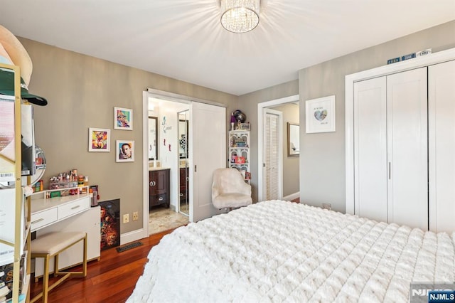 bedroom with connected bathroom, a notable chandelier, baseboards, visible vents, and dark wood-style floors