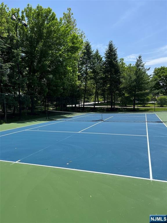view of tennis court with community basketball court and fence