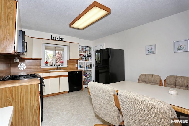 kitchen featuring a sink, wood counters, decorative backsplash, light tile patterned floors, and black appliances