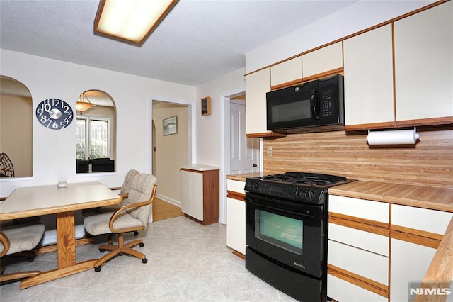kitchen with light countertops, white cabinetry, arched walkways, backsplash, and black appliances