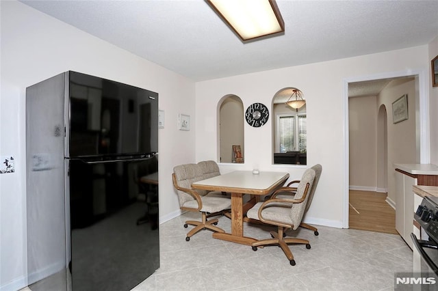dining room featuring baseboards, arched walkways, and light tile patterned flooring