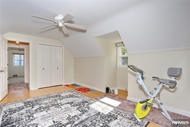 exercise area featuring plenty of natural light, a ceiling fan, baseboards, and wood finished floors