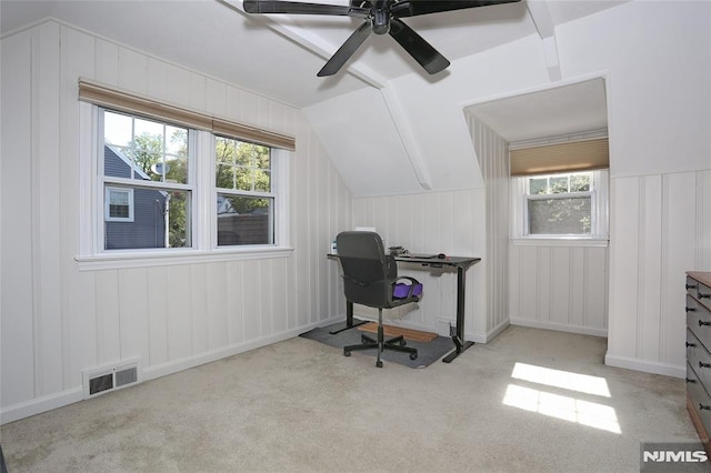office area featuring carpet flooring, a decorative wall, a ceiling fan, vaulted ceiling, and visible vents
