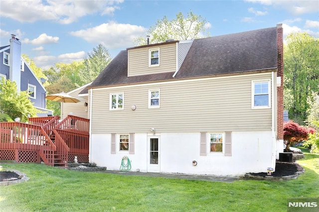 rear view of property featuring a yard, a deck, and stucco siding