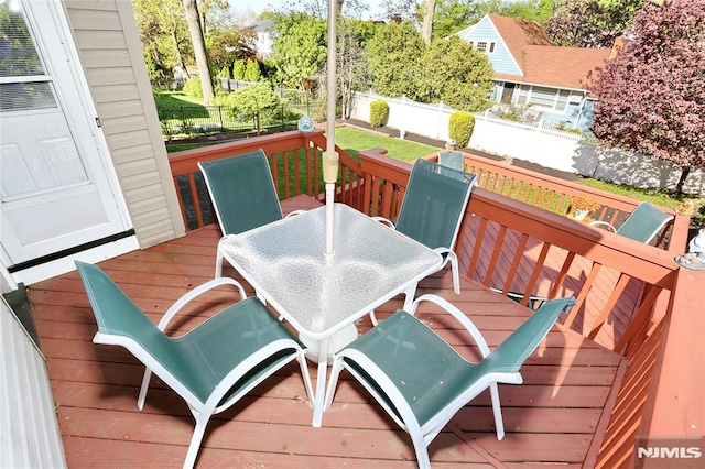 wooden deck with a fenced backyard and outdoor dining space