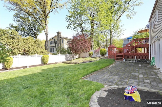 view of yard with a fenced backyard, a wooden deck, and a patio area