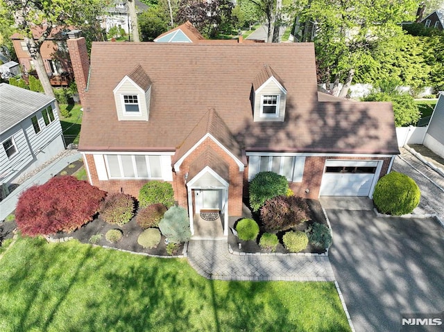 view of front of house with roof with shingles, driveway, and brick siding