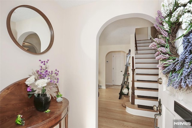 interior space featuring stairs, arched walkways, and light wood-type flooring