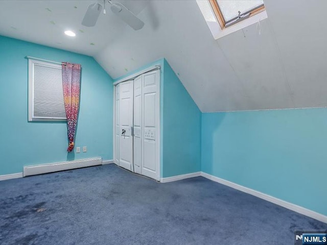 additional living space with a baseboard radiator, lofted ceiling with skylight, ceiling fan, carpet floors, and baseboards