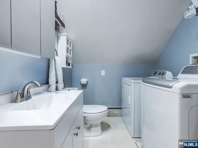 bathroom featuring washing machine and dryer, vaulted ceiling, vanity, and toilet