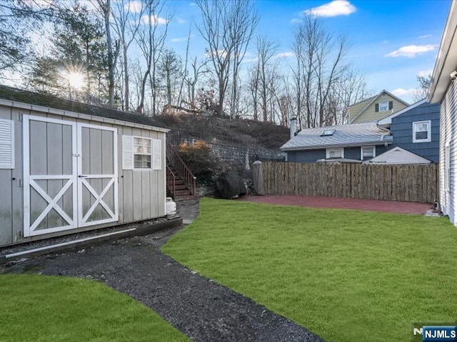 view of yard with fence, a storage unit, an outdoor structure, and stairway