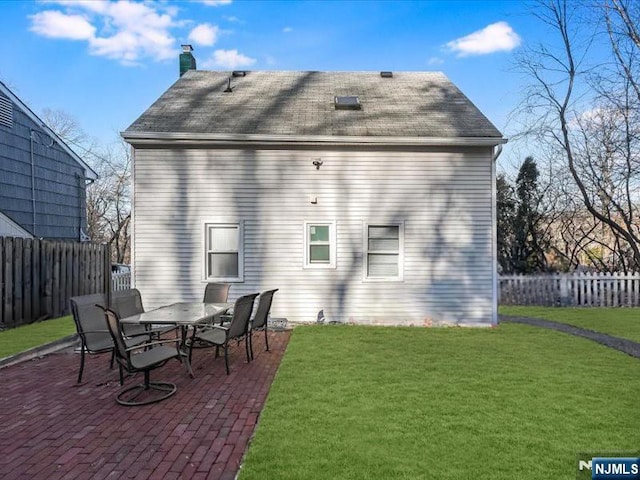 back of house featuring a fenced backyard, a yard, and a chimney