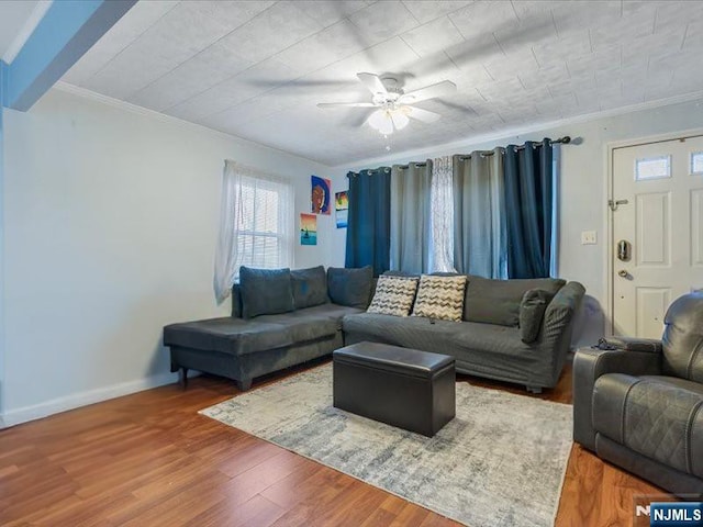 living area featuring baseboards, a ceiling fan, wood finished floors, and ornamental molding