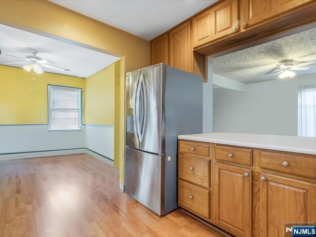kitchen featuring brown cabinets, stainless steel refrigerator with ice dispenser, and a ceiling fan