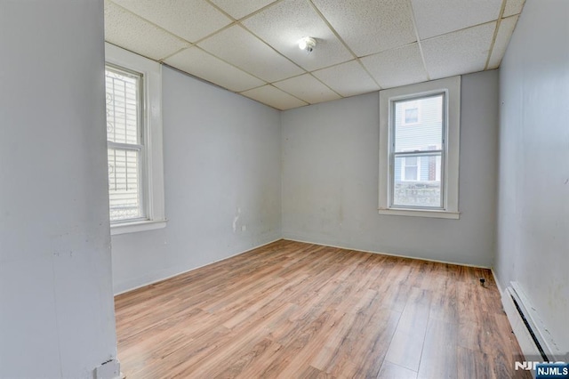 empty room with a baseboard heating unit, a paneled ceiling, and a wealth of natural light