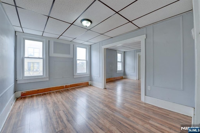 unfurnished room featuring baseboards, wood finished floors, and a paneled ceiling
