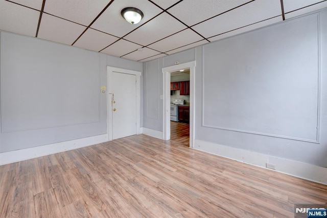unfurnished room featuring light wood-style flooring and a drop ceiling