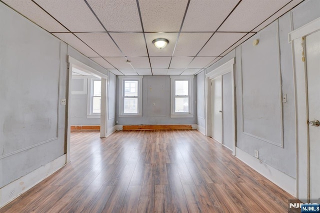 unfurnished room with a paneled ceiling, baseboards, and wood finished floors