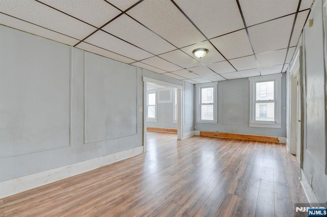 unfurnished room featuring baseboards, wood finished floors, and a drop ceiling
