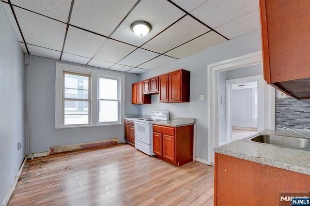 kitchen featuring white electric range, a drop ceiling, light countertops, a sink, and light wood-style flooring
