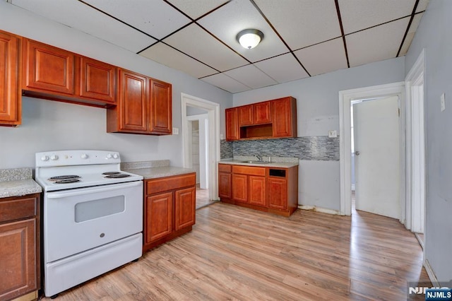 kitchen featuring light wood finished floors, white range with electric stovetop, a paneled ceiling, and light countertops