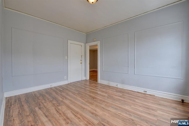 spare room featuring baseboards and wood finished floors